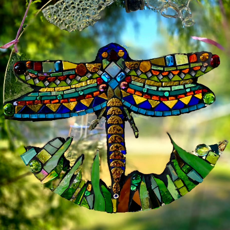 Mosaik-Libelle mit Ankerform Eine farbenfrohe Mosaik- oder Buntglas-Hängekunst einer Libelle mit detaillierten Flügeln über einem gebogenen grünen, ankerartigen Sockel,