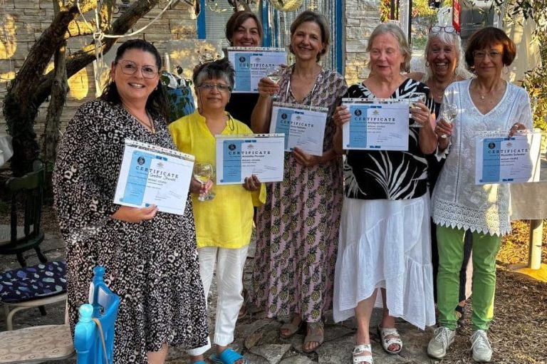 Feierliche Zertifikatsübergabe Ovales Foto einer Gruppe von sechs lächelnden Frauen, die im Freien stehen und stolz Zertifikate in die Kamera halten, einige mit Gläsern in