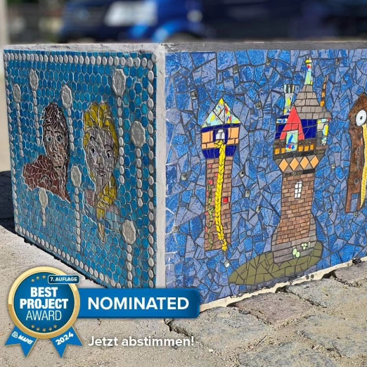 Nominiertes Mosaik-Projekt Mosaik-Block mit blauen Fliesen und zwei stilisierten Figuren, dekoriert mit einem "Best Project Award 2024 Nominated"-Siegel.