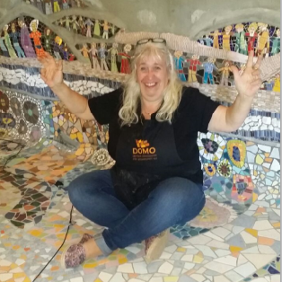Caroline Jung – Leidenschaft für Mosaikkunst Mosaikkünstlerin Caroline Jung präsentiert lächelnd eines ihrer großformatigen Mosaik-Kunstwerke.
