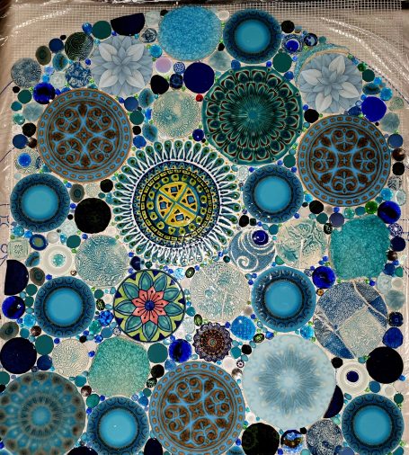 Kunstvolles Mosaikbild aus unzähligen blauen und türkisen Kreiselementen und floralen Mustern von Caroline Jung.