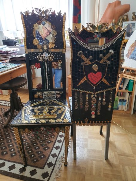 Verzierte gotische Mosaik-Stühle Zwei aufwendig gestaltete, dunkle Stühle mit Mosaik- und Spiegeldekorationen; einer mit Herzmotiv, der andere mit religiösen Elementen.