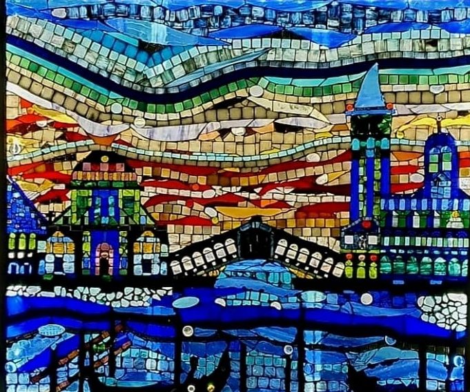 Detailreiches Mosaikbild einer abendlichen Stadtlandschaft mit einer Brücke über einem Kanal, umgeben von bunten, wellenförmigen Himmelsmust