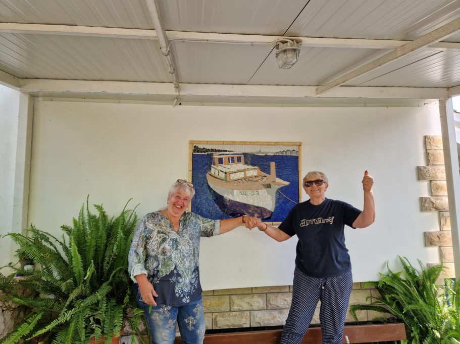 Mosaikkünstlerin Caroline Jung und eine Kundin freuen sich stolz über das fertig installierte maritime Wandmosaik.
