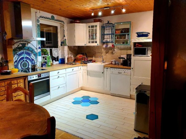 Fertiggestellte Küche mit einem beeindruckenden blauen Mosaik-Fliesenspiegel von Caroline Jung und passenden Bodenfliesen.