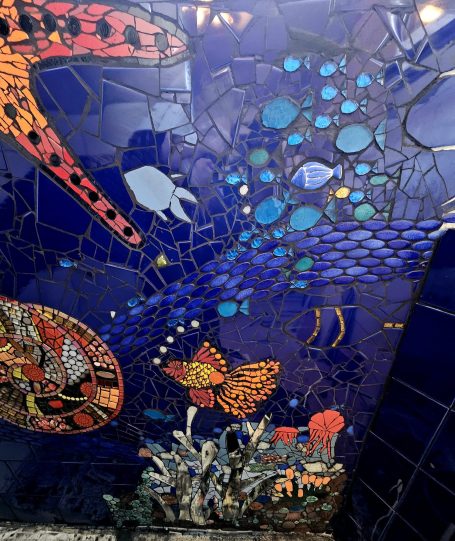 Detailreiches Mosaikbild eines leuchtenden Fisches in einer blauen Unterwasserwelt von Caroline Jung.