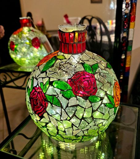 Mosaik-Kugel "Rote Rosen" Beleuchtete gläserne Mosaik-Kugel mit leuchtend roten Rosenblüten und grünen Blättern.
