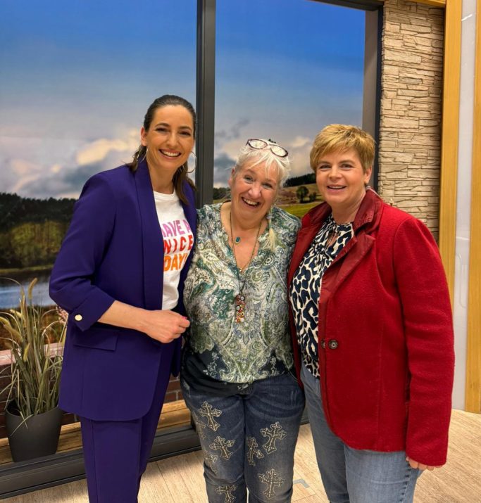 Strahlende Gesichter im TV-Studio Caroline Jung lächelt fröhlich zusammen mit der TV-Moderatorin und einer weiteren Frau im Studio der Sendung "Wir in Bayern".