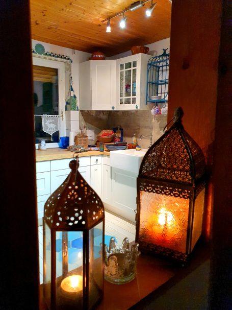 Stimmungsvolle Küchengestaltung mit orientalischen Laternen im Vordergrund und einem handgemachten Wandmosaik im Hintergrund.