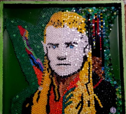 Mosaik-Porträt "Elbenprinz" Mosaik-Porträt von Legolas aus "Herr der Ringe" mit blonden Haaren vor grünem Hintergrund.