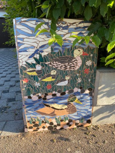 Mosaik-Ententeich-Paneel Vertikale rechteckige Mosaik-Säule, die eine stilisierte Ente auf dem Wasser zwischen Schilf darstellt.